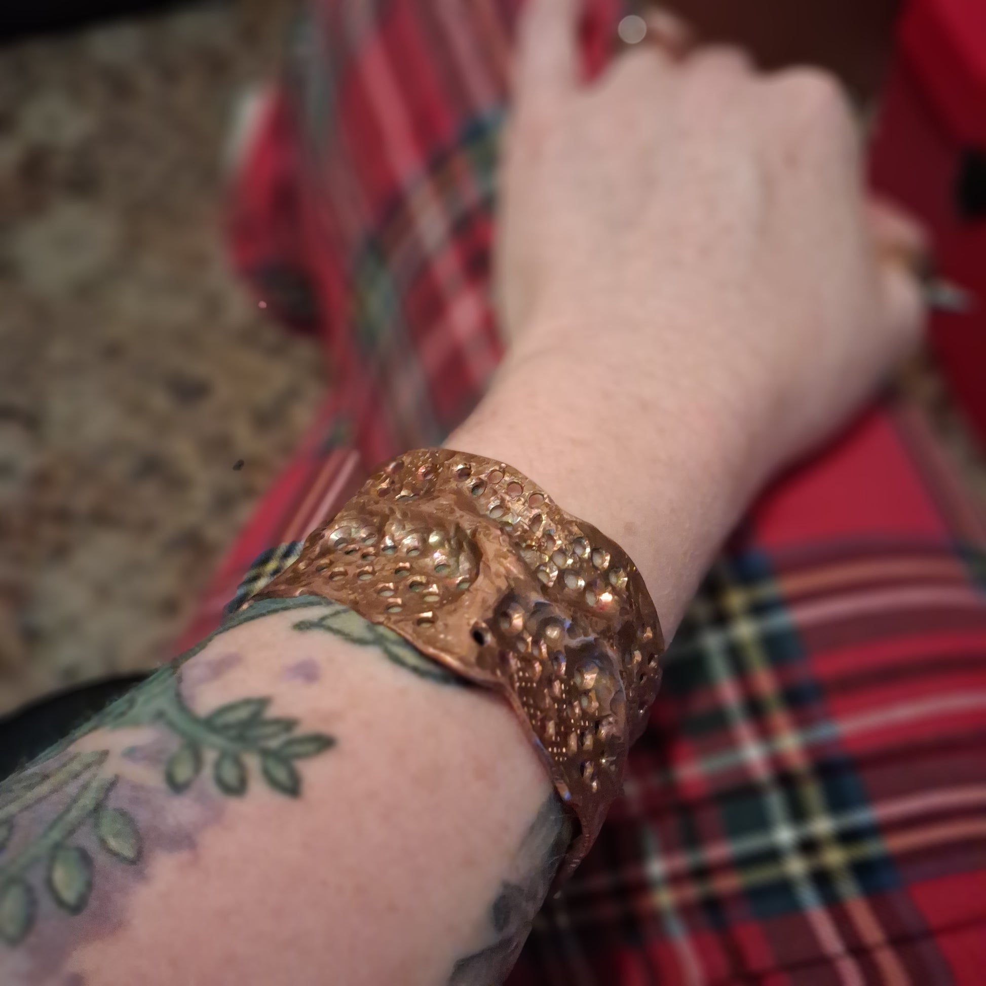 Close-up of a person's arm wearing a copper bracelet with a blurred background
